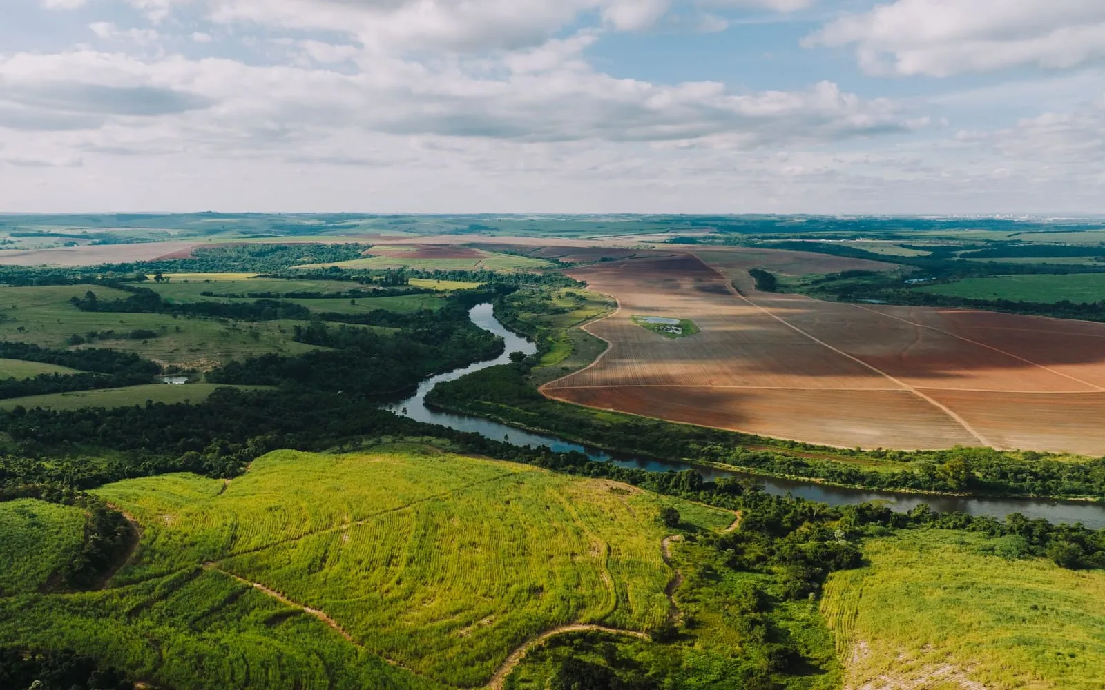 Vista aérea de área rural com campos verdes e rio